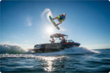 Wakeboarder launching off a wake boat