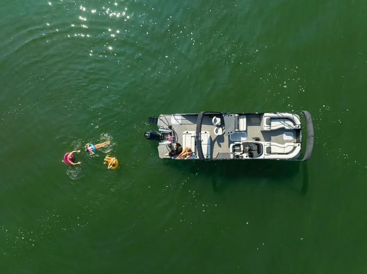 Overhead view of a pontoon and swimmers on a green lake
