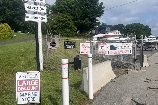 Freshly paved entrance to Petzold&rsquo;s Marine Center boatyard in Portland, CT, with restored directional and security signs displayed along the gate
