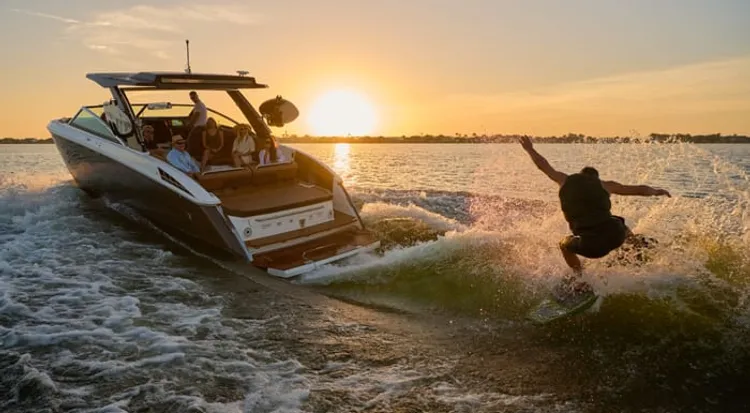 Wakesurfer riding behind a boat at sunset